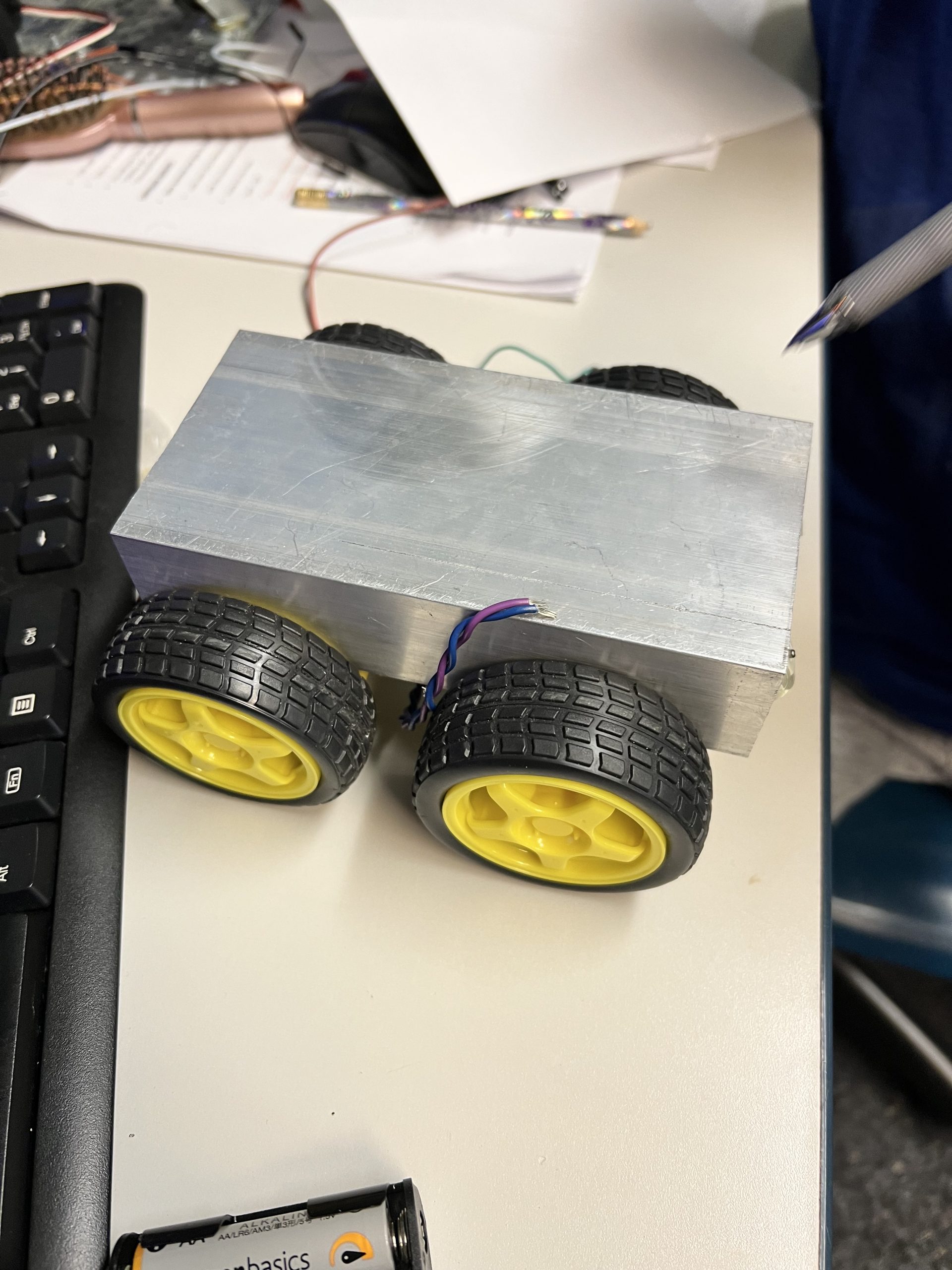 Aluminum 4WD robot chassis with yellow wheels on workbench at Plum Crazy Robotics
