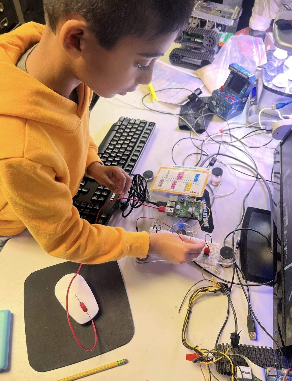 Student building breadboard circuit with Raspberry Pi and tracked robot at Plum Crazy Robotics Marlboro NJ
